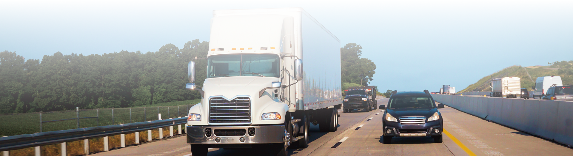 A large white semi-truck driving on a sunny highway.